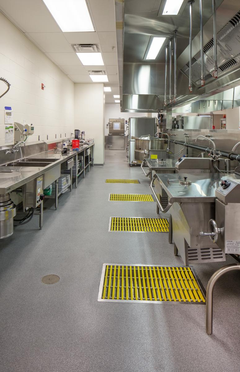 Commercial kitchen with a joint-free resinous floor, stainless sinks and floor mats