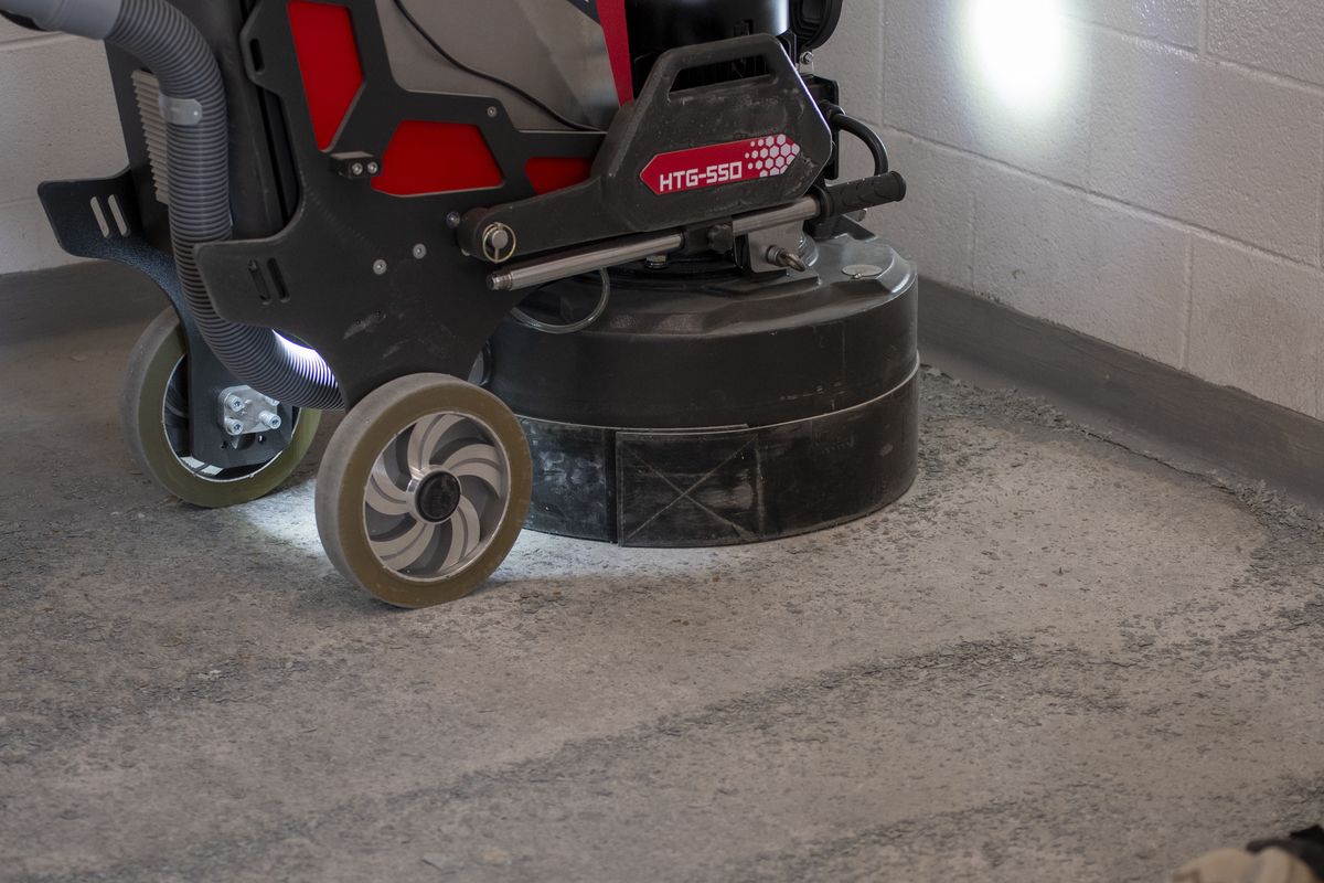 Floor grinder removing an old coating from a concrete slab