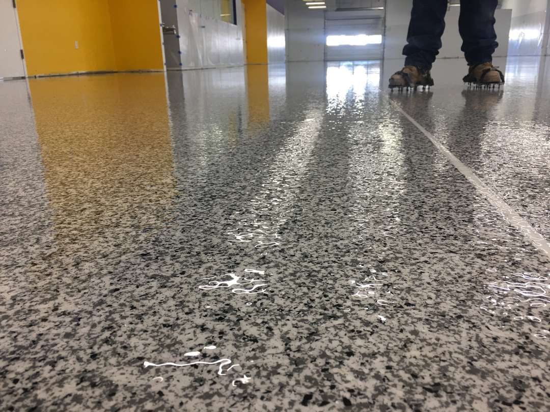 Clear topcoat being applied over a broadcast flake floor