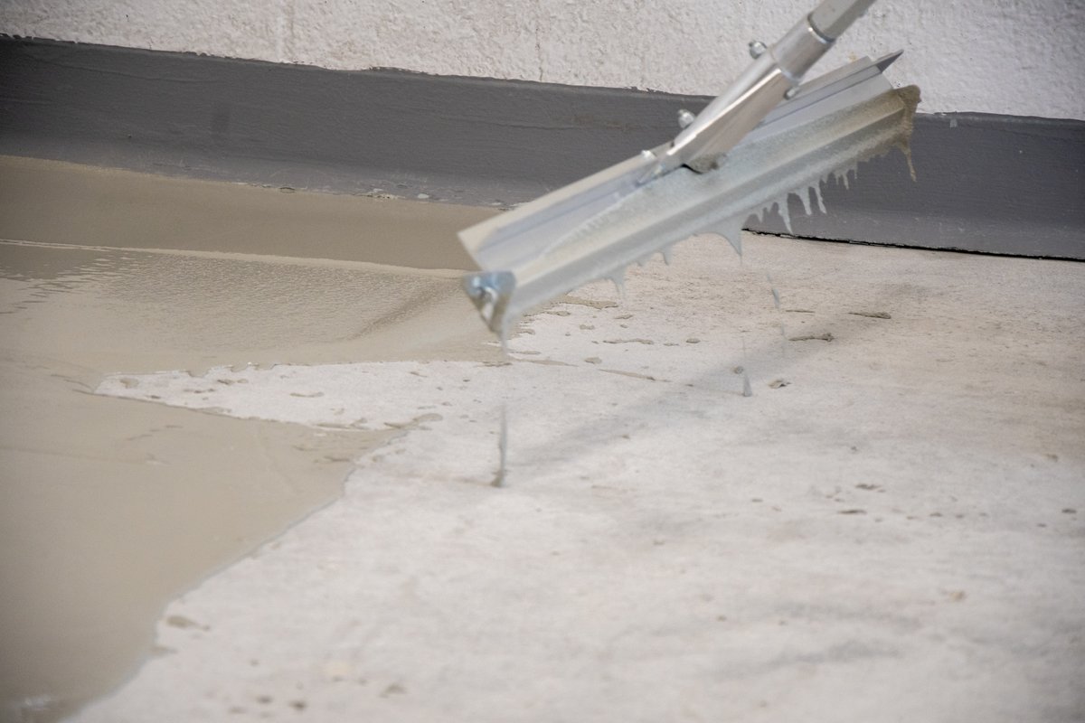 Gauge rake spreading self-leveling floor material